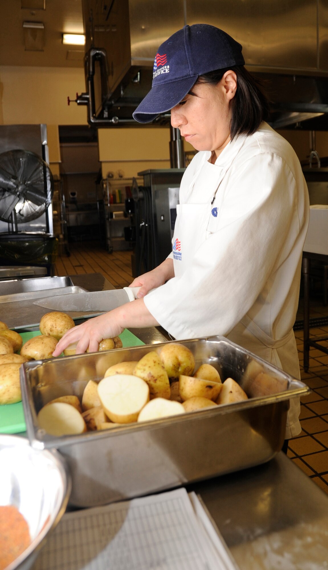 MISAWA AIR BASE, Japan -- Midori Ishioka, 35th Force Support Squadron contract cook, slices potatoes for dinner at the Grissom Dining Facility here, Jan. 26. The DFAC staff prepares for meals at least two hours before dining hours begin to ensure hot meals for all dorm residents. The DFAC follows a 14-day rotating menu supplied by the Air Force. (U.S. Air Force photo/Airman 1st Class Kaleb Snay)