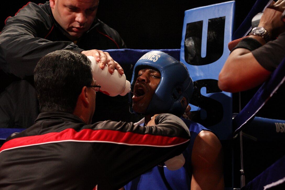 Lance Cpl. Johnathan Steele rests while his team coaches him to his final round of the night. Steele proceeds to his final round for yet another victory for the United States Marine Corps at the Armed Forces Boxing Championship at Paige Fieldhouse Feb. 1.::r::::n::