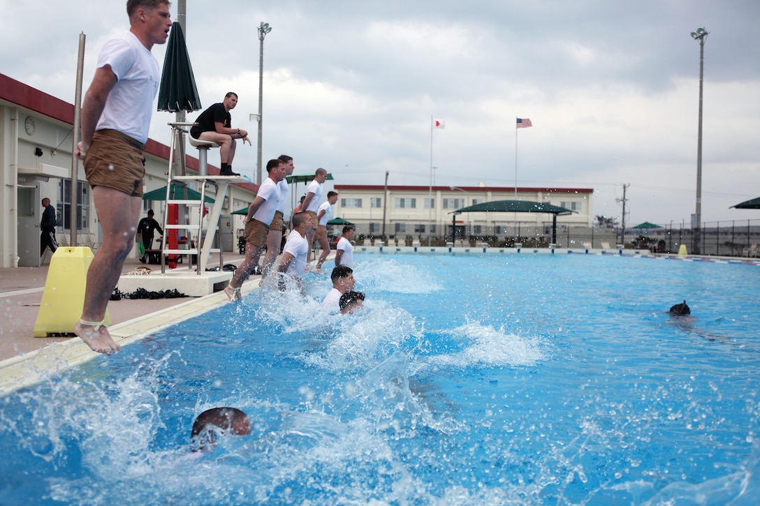 Reconnaissance Marines enter the water with their ankles bound and hands clenched tightly together during the initial stage of a proficiency screening at the aquatics center on Camp Schwab Feb. 2. The screening was conducted to determine which of the Marines are prepared to go to the U.S. Marine Corps Combat Diving School in Panama City, Fla. The Marines are with 3rd Reconnaissance Battalion, 3rd Marine Division, III Marine Expeditionary Force.