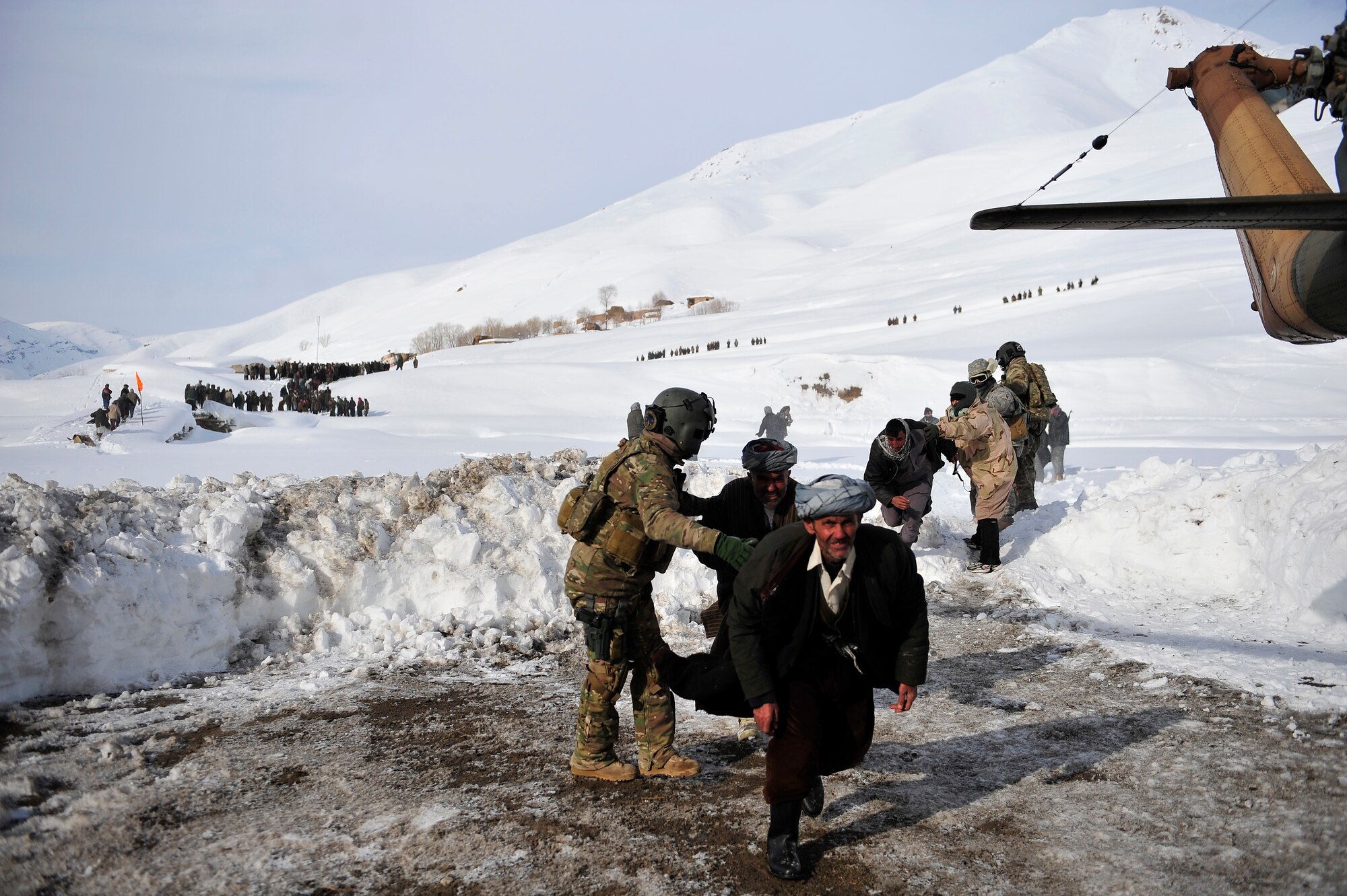 Staff Sgt. Jonathan Hill, an Mi-17 helicopter engineer from the 438th Air Expeditionary Advisory Squadron, who is deployed from the 36th Rescue Flight at Fairchild, directs villagers to his helicopter Jan 24. American and Afghan Airmen conducted a rescue mission in the Badakshan Province, Afghanistan after an avalanche trapped and injured members of Shewa Village. (U.S. Air Force photos by Master Sgt. Shane A. Cuomo)