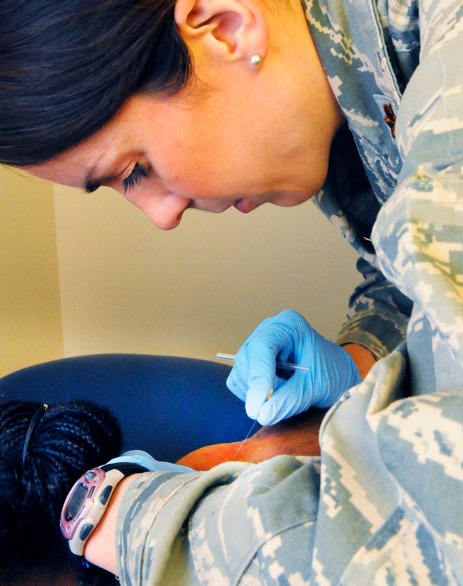 Maj. Ember Johnston places a needle into a patient. The dry needling relieves knots in muscles called trigger points. U. S. Air Force photo by Sue Sapp