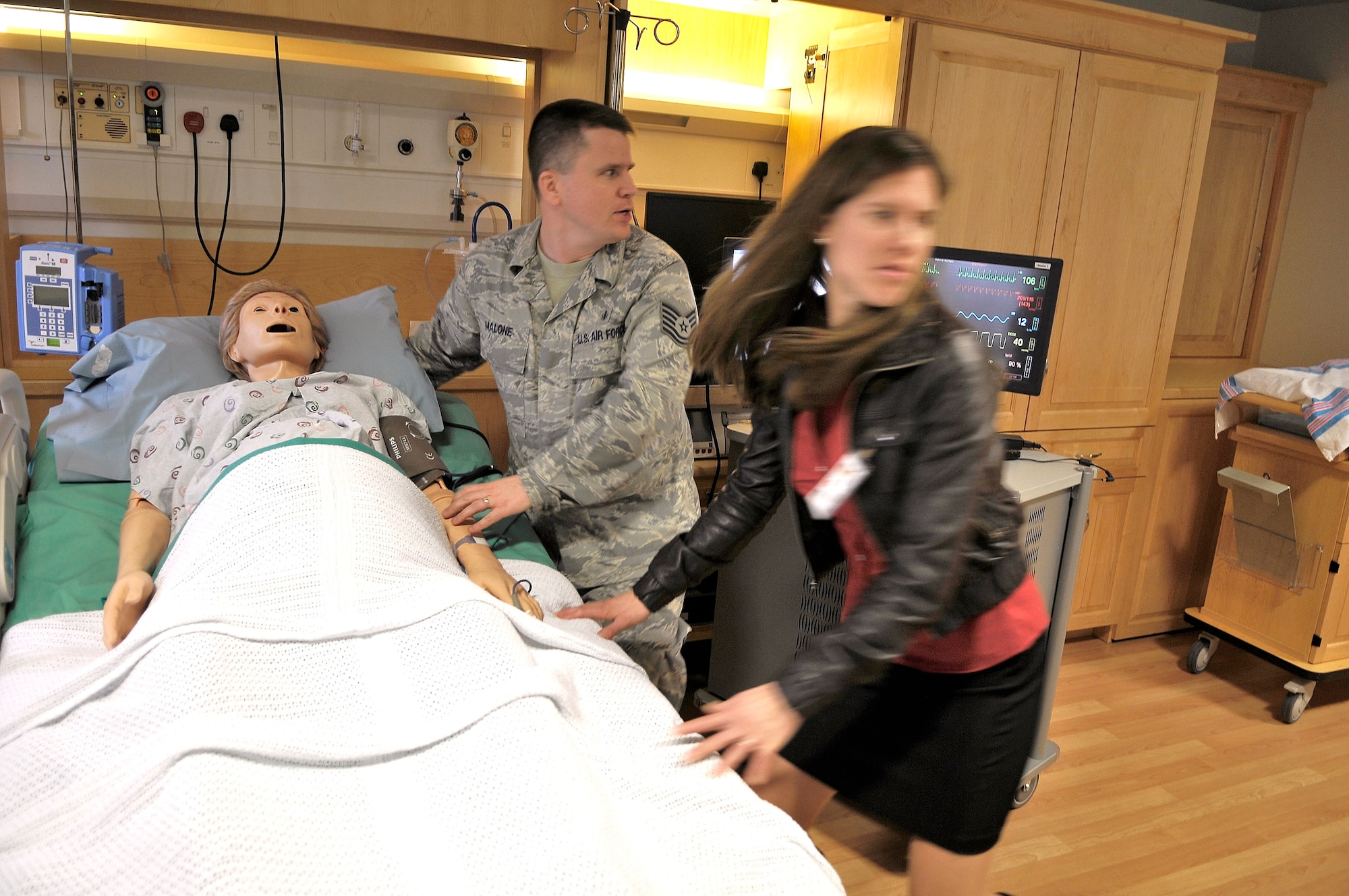 ROYAL AIR FORCE LAKENHEATH, England - Tech. Sgt. Victor Malone, (left) 48th Medical Group clinical education and training NCO in charge calls for help for a mannequin having simulated seizures as Valerie Colgate, 48th MDG medical simulation technician, runs to get more help at the 48th MDG hospital, Jan. 25, 2012.  The sim center uses a wide variety of scenarios, which include mannequins or better known as "patient simulators" in a myriad of medical emergency situations to help train medical personnel.  (U.S. Air Force photo by Staff Sgt. Connor Estes)