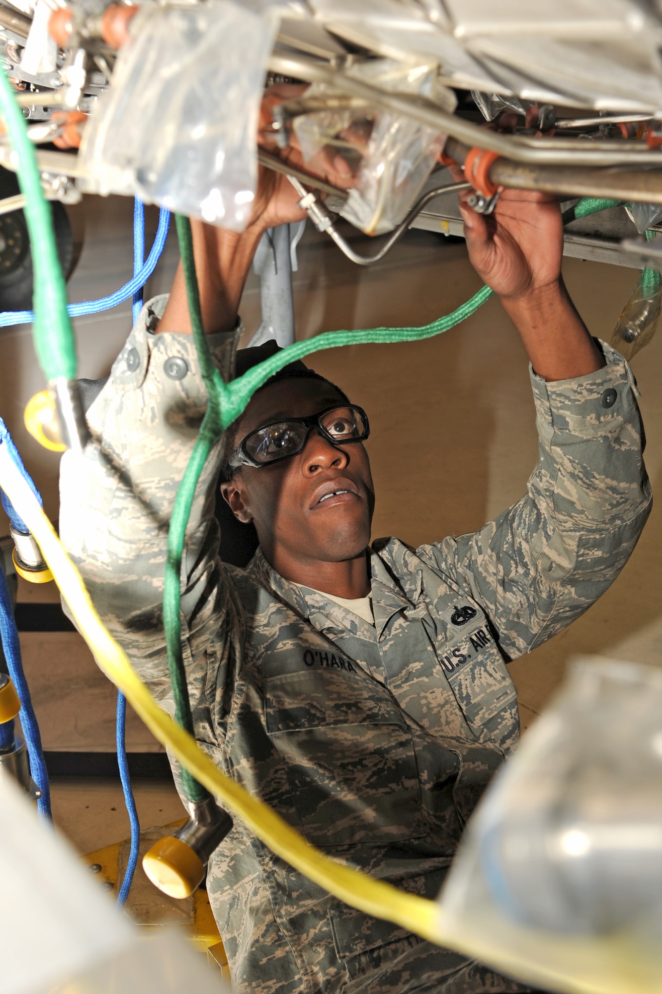 U.S. Air Force Staff Sgt. Vincent O’Hara runs exterior cables under an F-15 Strike Eagle engine while performing maintenance repairs on Seymour Johnson Air Force Base, N.C., Jan. 30, 2012. There are eight exterior cables matted to the engine to prevent cable chafing. The external cables are connected to the digital electric engine control which processes information from the aircrew to the engine. O’Hara is a 4th Component Maintenance Squadron jet engine intermediate mechanic from Waycross, Ga. (U.S. Air Force photo/Senior Airman Whitney Stanfield/Released)