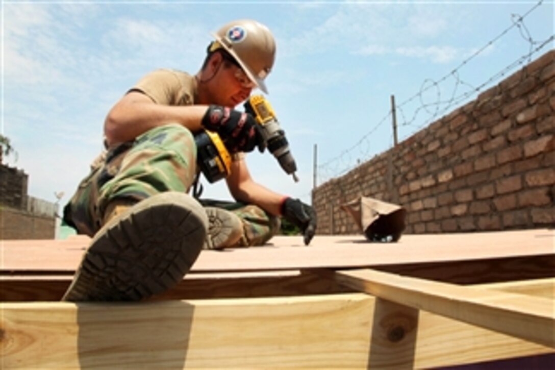 U.S. Navy Petty Officer 2nd Class Michael McAfee drills to attach a roof to a new school during Southern Partnership Station 2012 in Callao, Peru, on Jan. 27, 2012.  McAfee is an equipment operator assigned to Navy Mobile Construction Battalion 23.  