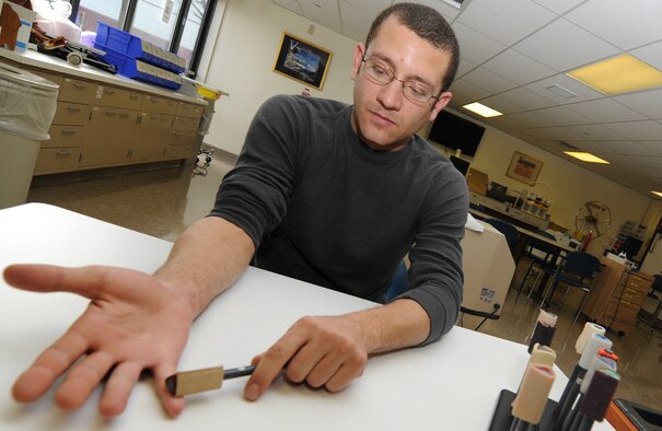 Petty Officer Third Class Chris McKee rubs materials of different types and textures during a scar desensitization therapy Feb. 1 at David Grant USAF Medical Center Occupational Therapy clinic. During a patient's therapy session materials of different types and textures are rubbed over the affected area to re-educate damaged nerves on that area. (U.S. Air Force photo/ Staff Sgt. Liliana Moreno)