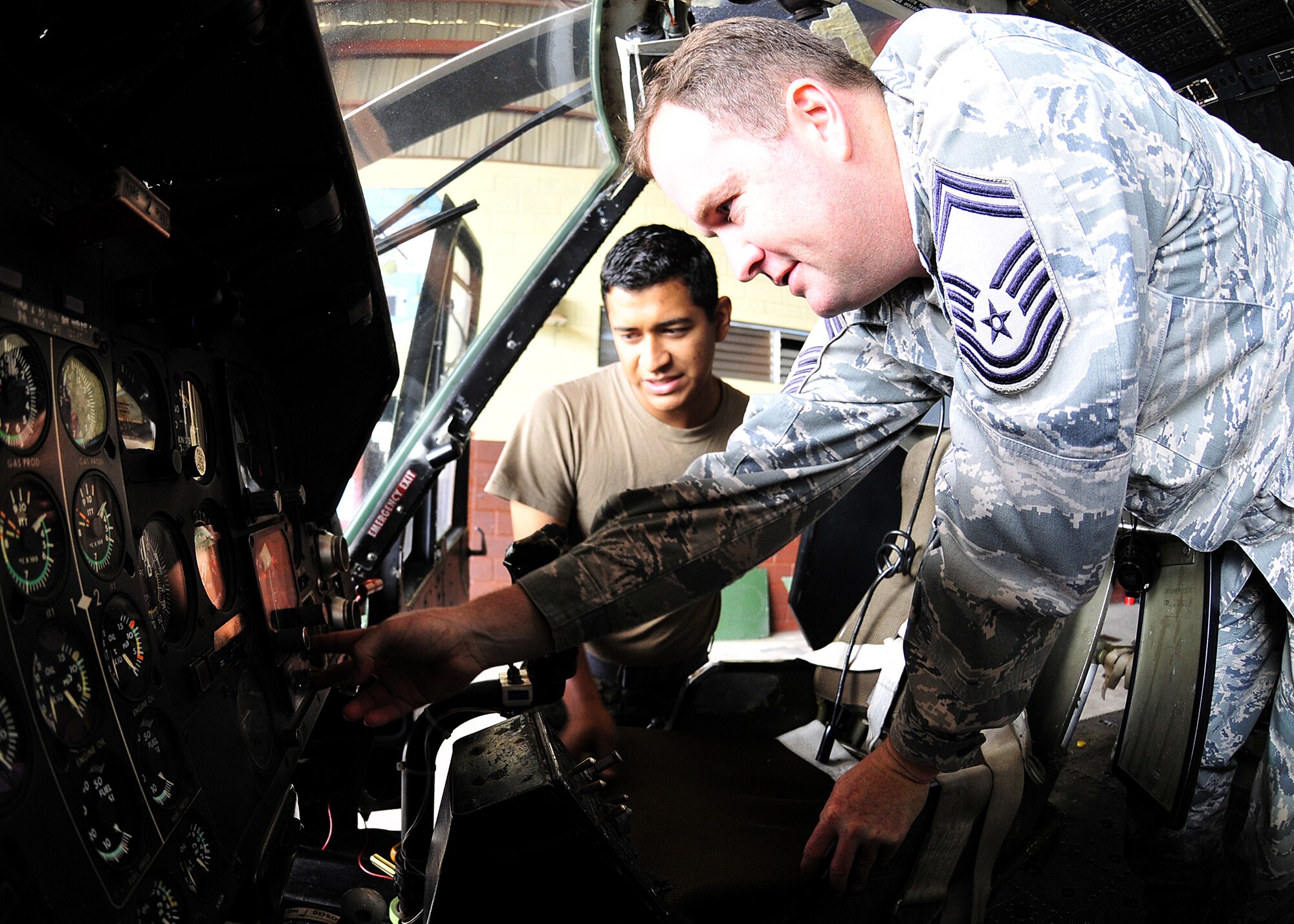 Senior Master Sgt. Hood, 571st Mission Support Advisory Squadron helicopter crew chief and air advisor, advises a Honduran Air Force member the proper installation of the radar altimeter indicator, in Tegucigalpa, Honduras, Feb. 3.  Radar altimeters are a component of terrain avoidance warning systems, warning the pilot if the aircraft is flying too low, or if there is rising terrain ahead. (U.S. Air Force photo by Tech. Sgt. Lesley Waters)