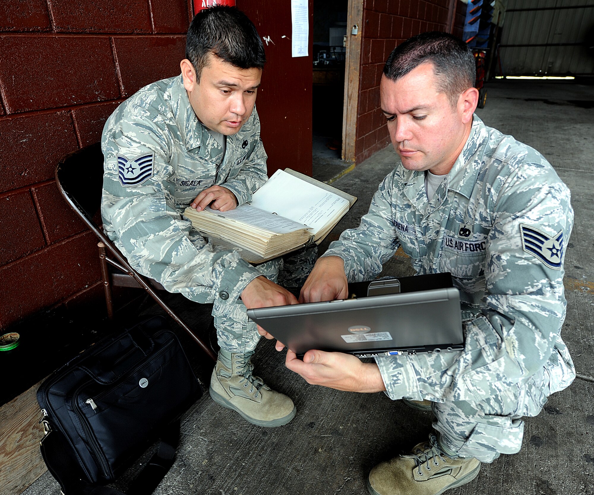 (Left) Technical Sgt. Ruben Sigala and Staff Sgt. Heric Llerena, Inter-American Air Forces Academy instructors, are looking in the manual and searching online for the technical data on how to properly install the radar altimeter on the helicopter, in Tegucigalpa, Honduras, Feb. 3.  Radar altimeters are a component of terrain avoidance warning systems, warning the pilot if the aircraft is flying too low, or if there is rising terrain ahead. (U.S. Air Force photo by Tech. Sgt. Lesley Waters)