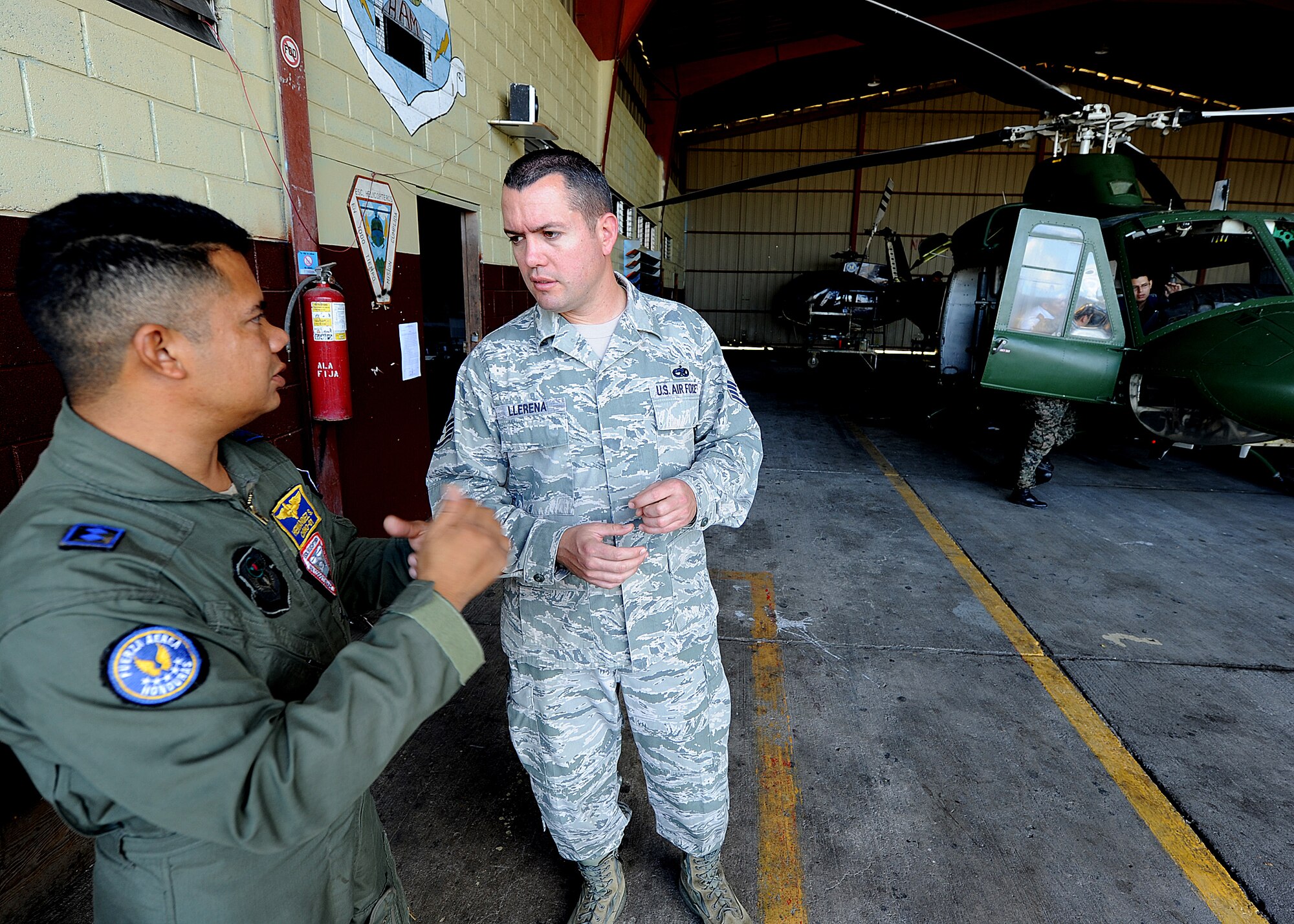 Staff Sgt. Heric Llerena, Inter-American Air Forces Academy instructor, discusses with a Honduran Air Force member safety concerns within the aircraft maintenance program, in Tegucigalpa, Honduras, Feb. 3.  Llerena is one of two Airmen from IAAFA working with the 571st Mobility Support Advisory Squadron in support of a month-long Building Partner Capacity mission in Honduras.  (U.S. Air Force photo by Tech. Sgt. Lesley Waters)