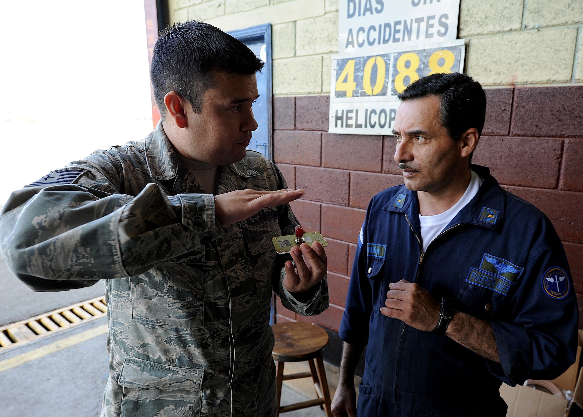 Technical Sgt. Ruben Sigala, Inter-American Air Forces Academy instructor, explains to a Honduran Air Force member the antenna placement on the helicopter tail boom, in Tegucigalpa, Honduras, Feb. 3. Sigala is one of two Airmen from IAAFA working with the 571st Mobility Support Advisory Squadron in support of a month-long Building Partner Capacity mission in Honduras.  (U.S. Air Force photo by Tech. Sgt. Lesley Waters)
