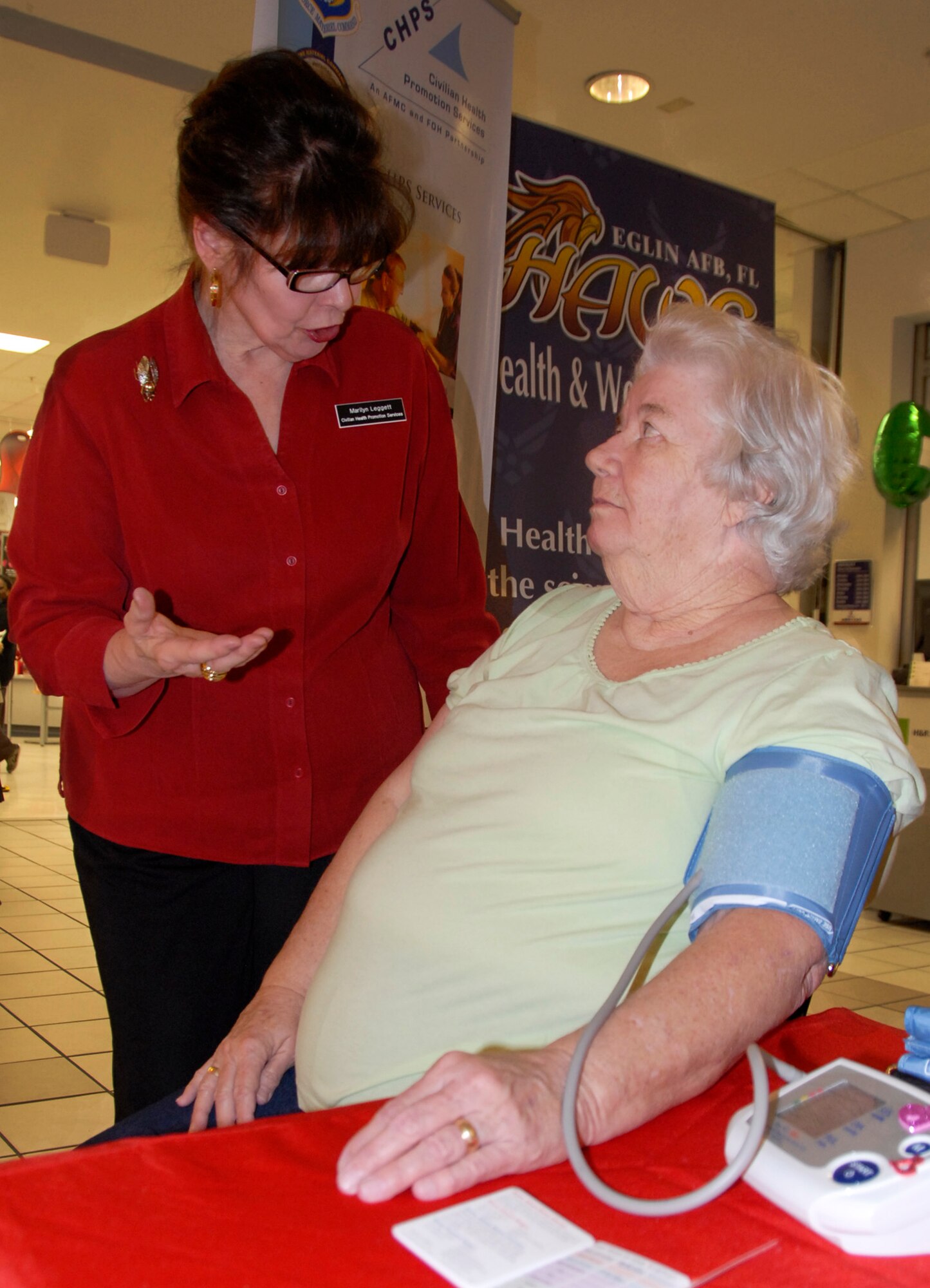 Marilyn Leggett, a Health and Wellness Center employee, gives Cathy Furtado a blood pressure check at the mini health fair, at the base exchange at Eglin Air Force Base, Fla., Feb. 3.  Leggett and other health care professionals offered patrons information on risk factors for heart disease, tobacco cessation and stress management.  The fair was held in conjunction with the American Heart Association’s national “Wear Red Day” campaign to heighten awareness about heart disease.  (U.S. Air Force photo/Kevin Gaddie)