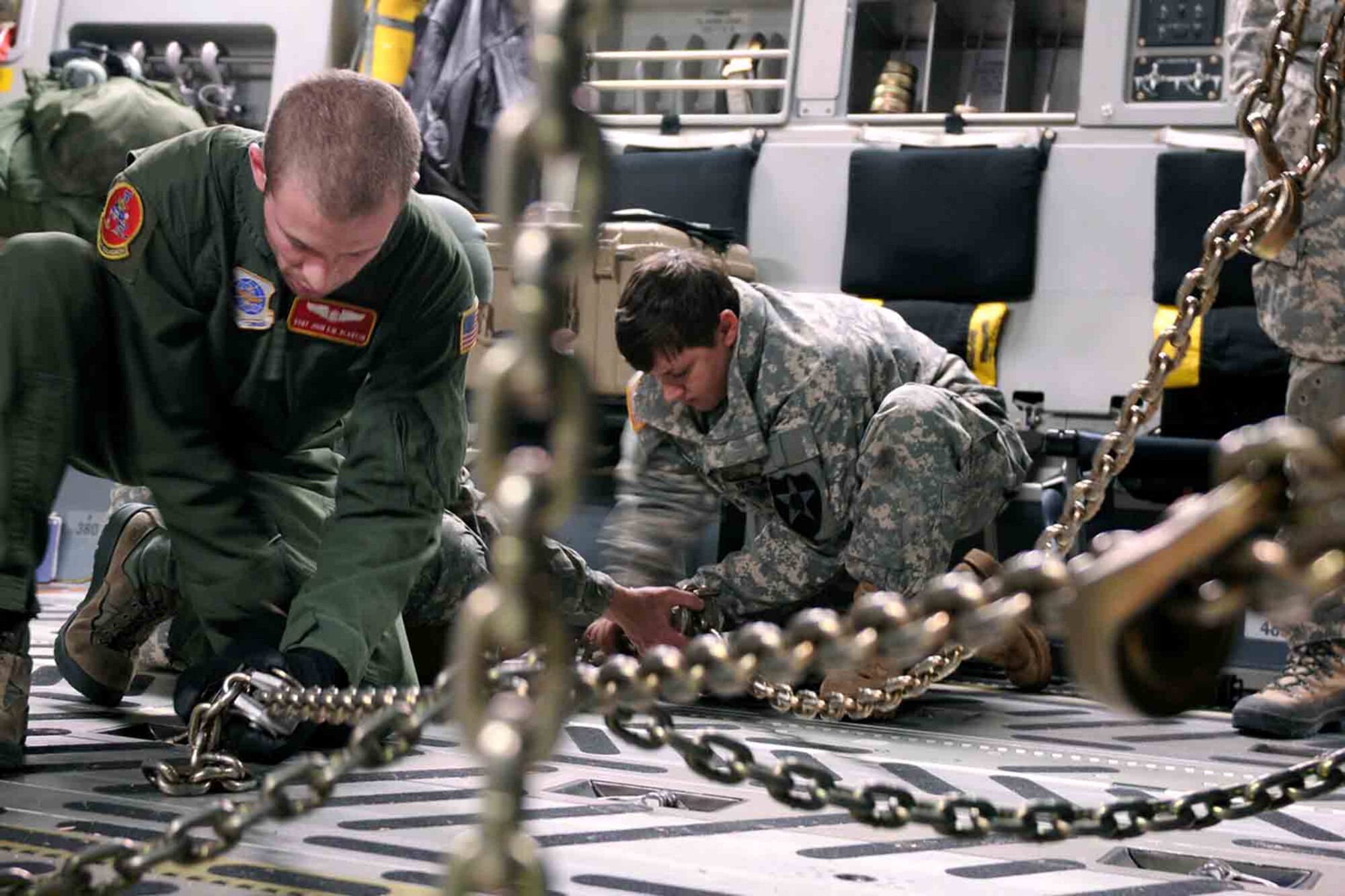Pfc. Jinnger Rogers (center), a signal systems support operator maintainer and Air Force Staff Sgt. John Blanton (left) secure 4th Stryker Brigade Combat Team, 2nd Infantry Division vehicles in the cargo hold of an Air Force C-17 Globemaster III aircraft from the 62nd Airlift Wing Jan. 28, 2012, at Joint Base Lewis-McChord, Wash. Soldiers of 4th SBCT, 2nd Inf. Div. are participating in Exercise Raider Focus, a monthlong brigade training exercise, and this marks the first time Strykers have been airlifted from JBLM to Yakima. (U.S. Army photo by Spc. Reese Von Rogatsz, 4th SBCT PAO, 2nd Inf. Div.)