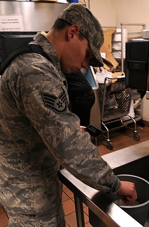 Staff Sergeant Ryan Melvin, 9th Aerospace Medicine Squadron public health technician, inspects the sanitizer solution at the Recce Point Club lunch bar at Beale Air Force Base, Calif., Jan. 31, 2012. Melvin uses chlorine test strips to measure the chlorine in parts per million to ensure the sanitizer is at the correct strength. (U.S. Air Force photo by Airman 1st Class Brittany Paerschke-O'Brien/ Released)
