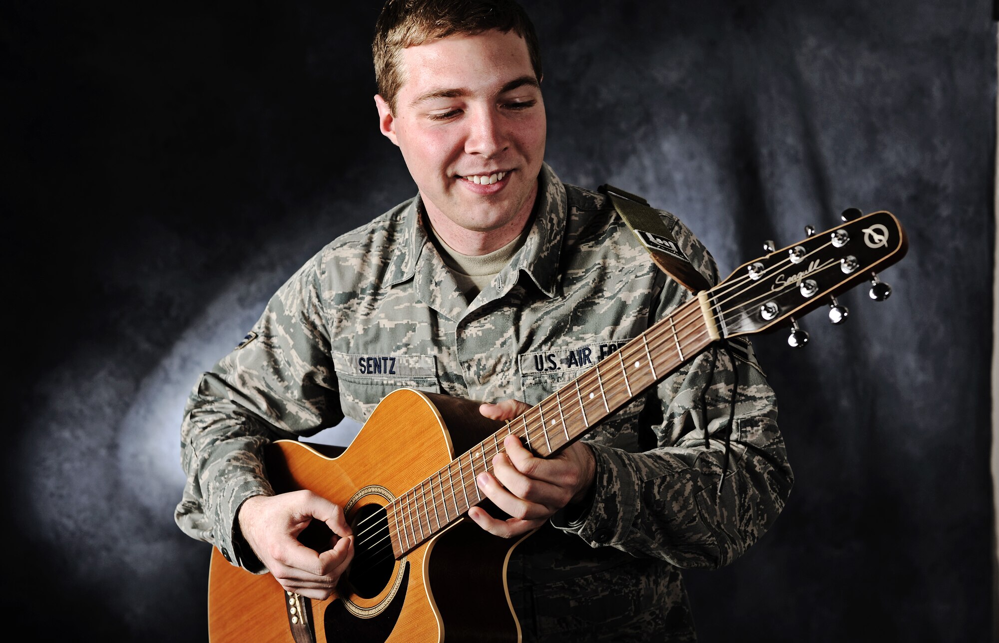 Airman 1st Class Timothy Sentz, 375th Communications Squadron client systems technician, plays his guitar as he gets his photo taken. Sentz was recently notified of his selection to be part of the 2012 Tops in Blue tour.(U.S. Air Force photo/Staff Sgt. Ryan Crane)