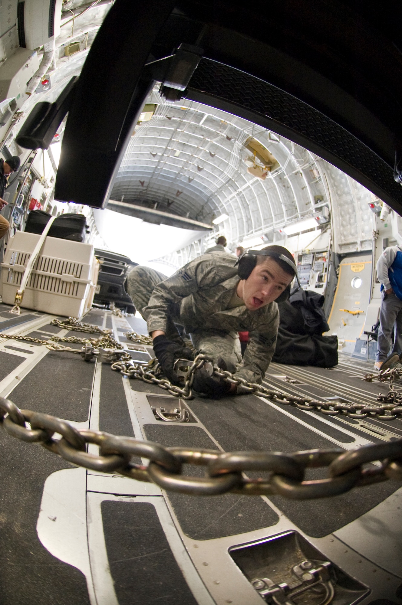 Senior Airman Michael Oniones, 89th Aerial Port Squadron aircraft services specialist, tightens down an MB-1 chain device to secure a government vehicle inside a C-17 aircraft during a presidential-level mission here Jan. 25. (Photo/Bobby Jones)