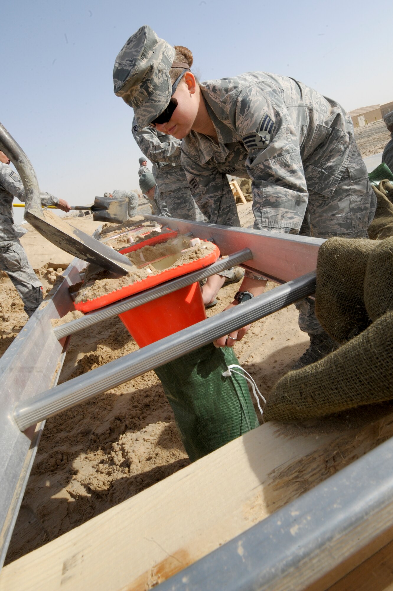 Senior Airman Celeste Vasalyga, 332nd Expeditionary Civil Engineer Squadron, catches sand at an undisclosed location in Southwest Asia, Feb. 3, 2012. The 332nd ECES spent the day building 2,500 sandbags to determine the exact amount necessary to protect one safety bunker. Vasalyga is deployed from Peterson Air Force Base, Colo., and is a native of Funk, Neb. (U.S. Air Force photo by Staff Sgt. Joshua J. Garcia/Released)