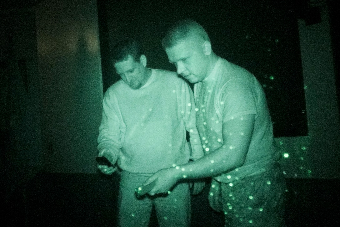 Air Force Capt. Stan Maczek, right, with fellow paranormal investigator Josh Burger, demonstrate the use of an electro-magnetic field detector through the lens of a video camera equipped with an infrared attachment on Schriever Air Force Base, Colo., Jan. 18, 2012. Maczek is assigned to the 1st Space Operations Squadron and Burger is an Air Force contractor. They hunt ghosts as a hobby. U.S. Air Force photo by Scott Prater