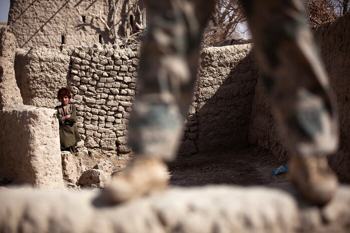 An Afghan boy watches Afghan Border Police Pvt. Ghul Faruq, a medic with 2nd Tolai, 2nd Kandak, Helmand ABP, provide security as fellow ABP search a compound during a partnered security patrol with U.S. Marines from Combined Anti-Armor Team 2, Weapons Company, 3rd Battalion, 3rd Marine Regiment, here, Jan. 30. In southern Garmsir district, an area with a history of tribal conflict, the growing ABP force has deepened its roots and established governance through the mentorship of the 3/3 Weapons Co. Marines. The ABP is younger and significantly smaller than the Afghan National Army and police forces, but its mission is vital as Afghan forces prepare to assume lead security responsibility in Garmsir. “If the ABP didn’t exist, there would be holes all along Afghanistan’s southern border,” said Capt. Jason Armas, 33, the commanding officer of Weapons Co., 3/3, and a native of Rye, N.Y.