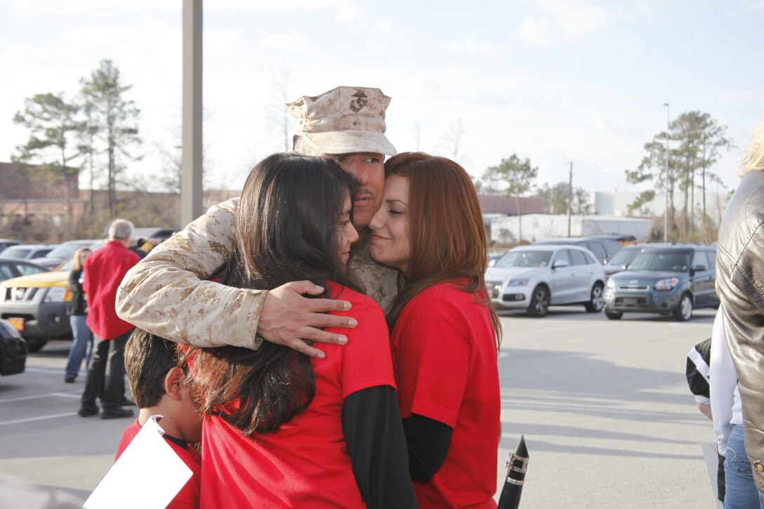 Staff Sgt. Alex Aguilar, an aviation information systems specialist with Marine Aviation Logistics Squadron 14 embraces his children, Eric and Brenda, and wife, Laura, after they re-unite at the Training and Education Building aboard Marine Corps Air Station Cherry Point Feb. 4, 2012. As the troops unloaded the bus, Brenda played God Bless America on her clarinet. "I wanted to play the song because my dad loved to listen to me practice when he was home," she said.