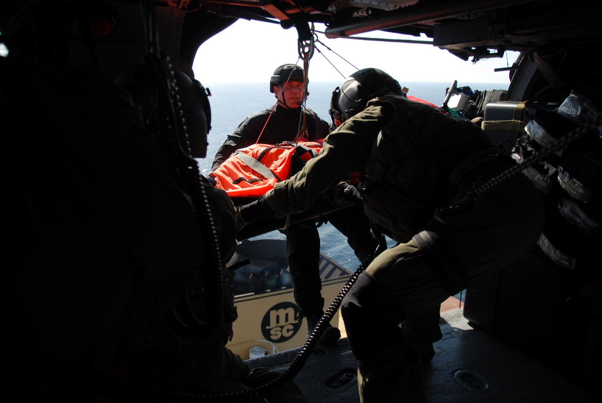 Tech. Sgt. Sean Pellaton, an aerial gunner assigned to the 129th Rescue Squadron, guides Staff Sgt. Adam Vanhaaster, a pararescueman assigned to the 131st Rescue Squadron, and his patient into the HH-60G Pave Hawk rescue helicopter Feb. 4, 2012. Responding to the call from the Eleventh District Coast Guard at Alameda, pararescuers, or PJs, two Pave Hawks and one MC-130P Combat Shadow aircraft departed Moffett Federal Airfield. The team provided medical assistance to a 54-year-old male who had suffered stroke-like symptoms on the MSC Beijing, acargo ship more than 200 miles off the coast of California. Guardsmen air lifted the patient to the San Jose Regional Medical Center. (Air National Guard photo by Senior Airman Jessica Green)