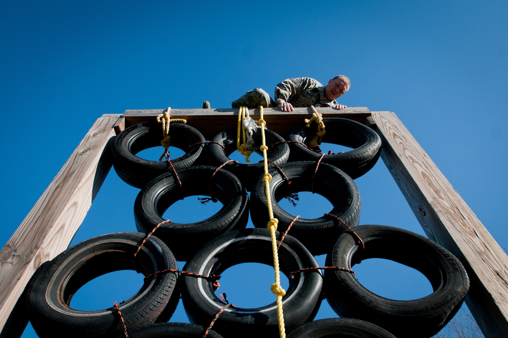 Master Sgt. Josh Devine, a member of the Kentucky Air National Guard's 123rd Security Forces Squadron, climbs over a tire tower at Southern High School in Louisville, Ky., Dec. 10, 2011. Airmen from the 123rd SFS were at the high school to use the Junior ROTC obstacle course for a team-building exercise as part of Wingman Day activities. (U.S. Air Force photo by Senior Airman Maxwell Rechel)