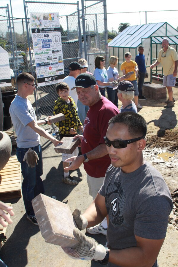 Petty Officer 2nd Class Jaime Garcia, hospital corpsmen, Marine Corps Recruit Depot San Diego Medical, helps unload bricks from a truck by grabing the first brick to pass down an assembly line at Taft Middle School Feb. 4. Military members from MCRD volunteered their weekend to help build a garden learning environment for the school. The project is a part of this year's Legacy Project, a community based project that involves schools that the American Society of Landscape Architects commits to providing active learning environments for the students.