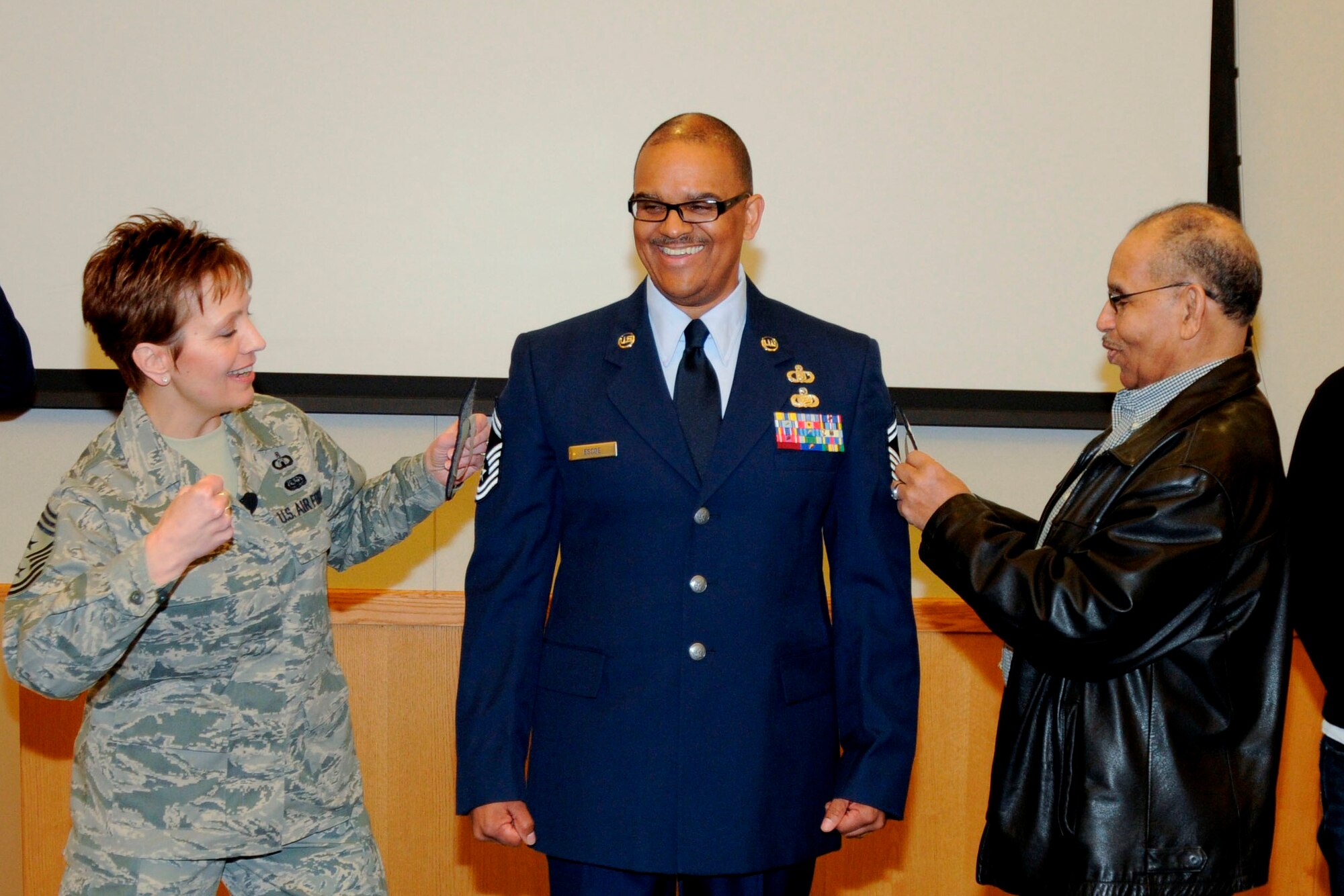 CMSgt. Denise Jelinski-Hall, senior enlisted leader of the National Guard Bureau, prepares to pin on the rank insignia of a chief master sergeant on to Walter Escoe, who was promoted to that rank during a Feb. 4, 2012 ceremony at Selfridge Air National Guard Base, Mich. New rank is traditionally “pinned” on to an Airman with a collegial punch in the arm. Pinning on the rank on the other arm Howard Goolsby, one of Escoe’s mentors. Jelinski-Hall visited Selfridge part of a tour of several Michigan National Guard facilities. At each stop, she spoke to Airmen and Soldiers and sought their input on issues to take back to the senior leaders of the Guard. (U.S. Air Force photo by TSgt. David Kujawa)