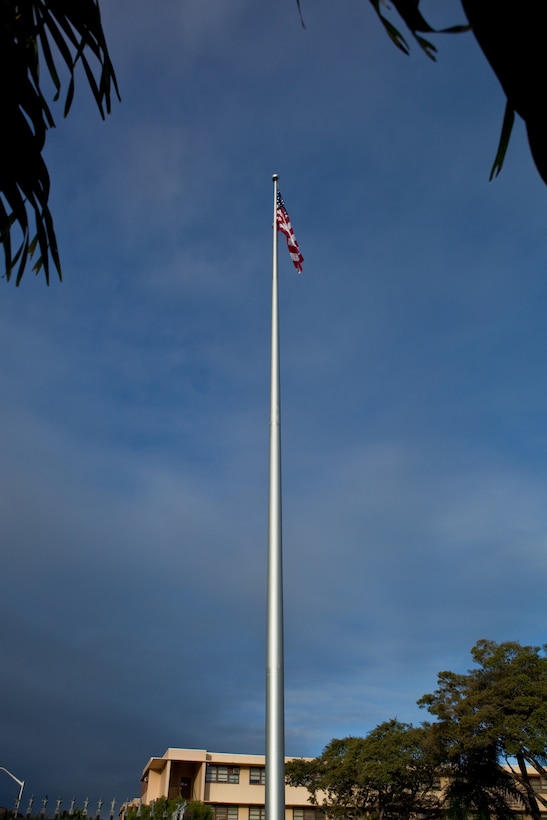 The national colors fly high above the headquarters building of U.S. Marine Corps Forces, Pacific, following a flagpole rededication ceremony here, Feb. 6. More than a hundred service members and civilians attended the flag raising and rededication ceremony. The MarForPac Band provided music throughout, to include playing the national anthem as a detail of Marines hoisted the flag. After standing tall for more than 56 years, the old flagpole had started to rust internally and needed to be replaced. The project forced a two-week hiatus of morning and evening colors aboard the base.
