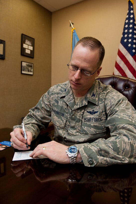 Col. Mark Weatherington, 28th Bomb Wing commander, signs the first pledge to kick off the 2012 Air Force Assistance Fund campaign at Ellsworth Air Force Base, S.D., Feb. 2, 2012. The AFAF was established to provide an annual effort to raise funds for the charitable affiliates that provide support to Air Force families in need. (U.S. Air Force photo by Airman 1st Class Kate Thornton/Released)