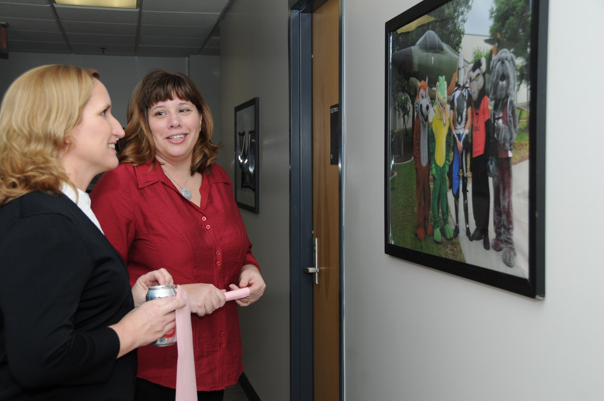 Valerie Mackin, spouse of Chief Master Sgt. Oscar “Deno” Mackin, 2nd Air Force command chief, and Keri Mueller, spouse of Brig. Gen. Andrew Mueller, 81st Training Wing commander, reflect on a photo of the 81st Training Group’s various mascots during a tour of the Levitow Training Support Facility, Keesler Air Force Base, Miss.  Keesler is home to 2nd Air Force headquarters and the first of six bases the new command chief is scheduled to tour through June.  (U.S. Air Force photo by Kemberly Groue)