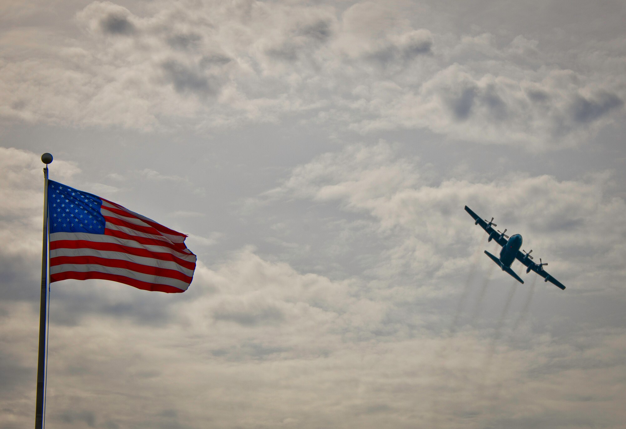 A C-130 soars by the Air Armament Center headquarters flag while doing some pattern work over Eglin Air Force Base’s flightline Feb. 3.  (U.S. Air Force photo/Samuel King Jr.)