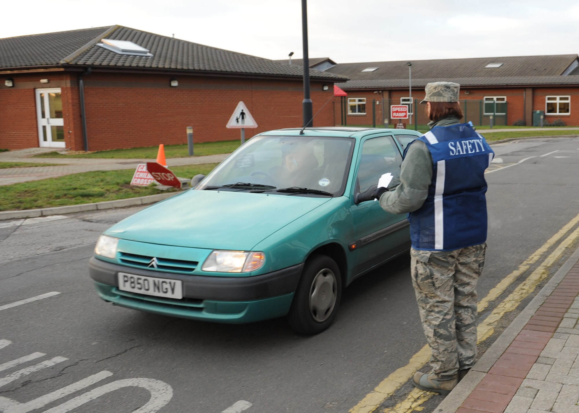 RAF MILDENHALL, ENGLAND – Tech. Sgt. Leigh Arriaga, with the 100 Air Refueling Wing’s Command Post, hands a no-right-turn flyer to an individual exiting the Child Development Center here Feb. 2, 2012. Airmen with the 100th Air Refueling Wing’s Safety Office and Command Post were handing out the flyers to increase awareness of the dangers of making illegal right hand turns when leaving the center and entering the highway. (U.S. Air Force photo/Tech. Sgt. Neal Joiner)