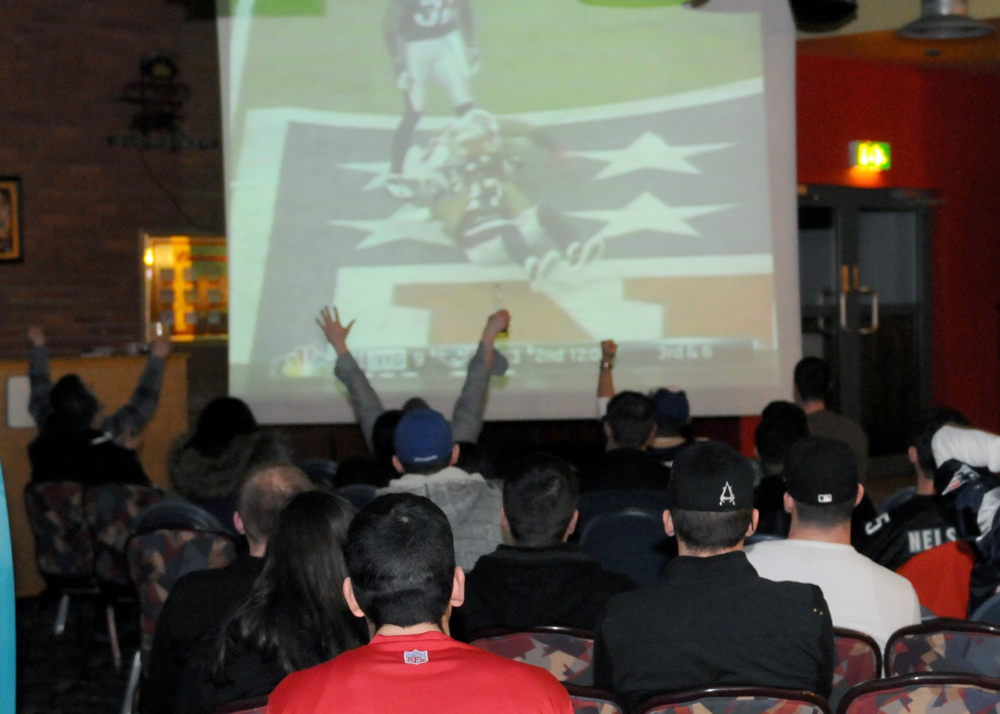 RAF MILDENHALL, England – Members of Team Mildenhall cheer for their 2012 Superbowl pick at the Galaxy Club Superbowl party here Feb. 5, 2012.  The party allowed military members to enjoy a little taste of home right here in England.  (U.S. Air Force photo/Staff Sgt. Tabitha M. Lee)