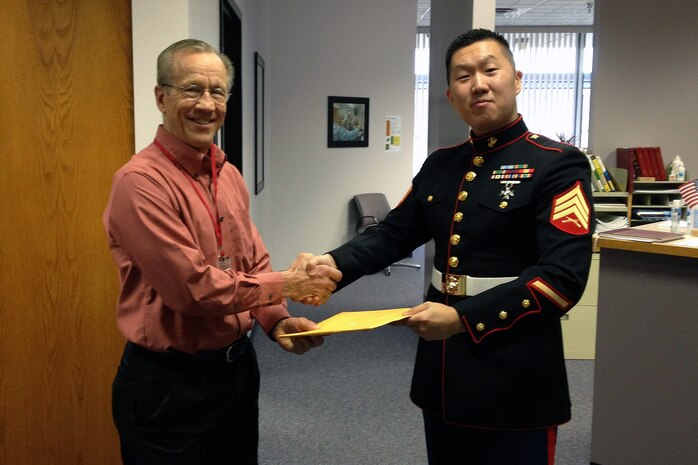 Woodbury, Minn., recruiter Sgt. Dae H. Kim presents a Glazier Clinic Minneapolis pass to St. Croix Lutheran High School head football coach Carl Lemke Feb. 7. Marines with Recruiting Station Twin Cities are working with high school coaches and educators to set up combat fitness tests for their student athletes.