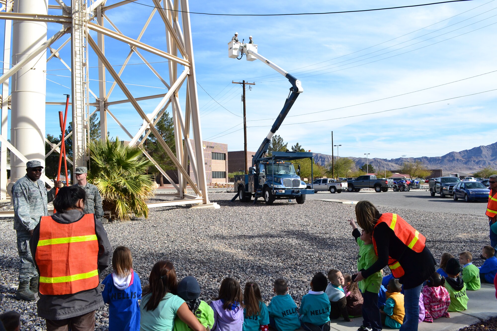 Children from the Nellis Child Development Center watch as Airmen from the 99th Civil Engineer Squadron are lifted toward the water tower Jan. 27, 2012, on Nellis Air Force Base, Nev.  The 99 CES Airmen accompanied the children on a field trip and taught them about the base water tower and other “giants” located around the base.  (Courtesy photo)