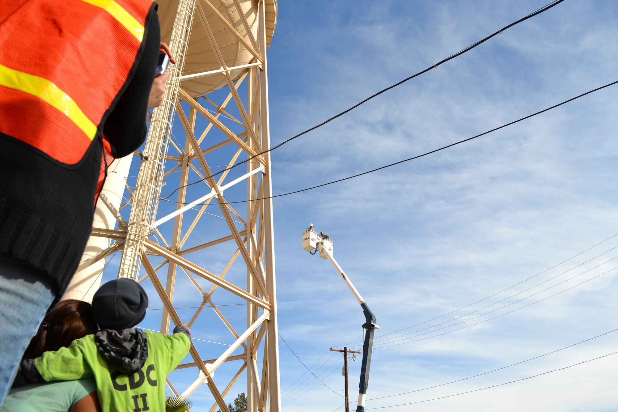 A child from the Nellis Child Development Center points to 99th Civil Engineer Squadron Airmen who are demonstrating one of their capabilities in a bucket lift Jan. 27, 2012, on Nellis Air Force Base, Nev.  The 99 CES Airmen accompanied the children on a field trip and taught them about the base water tower and other “giants” located around the base.  (Courtesy photo)
