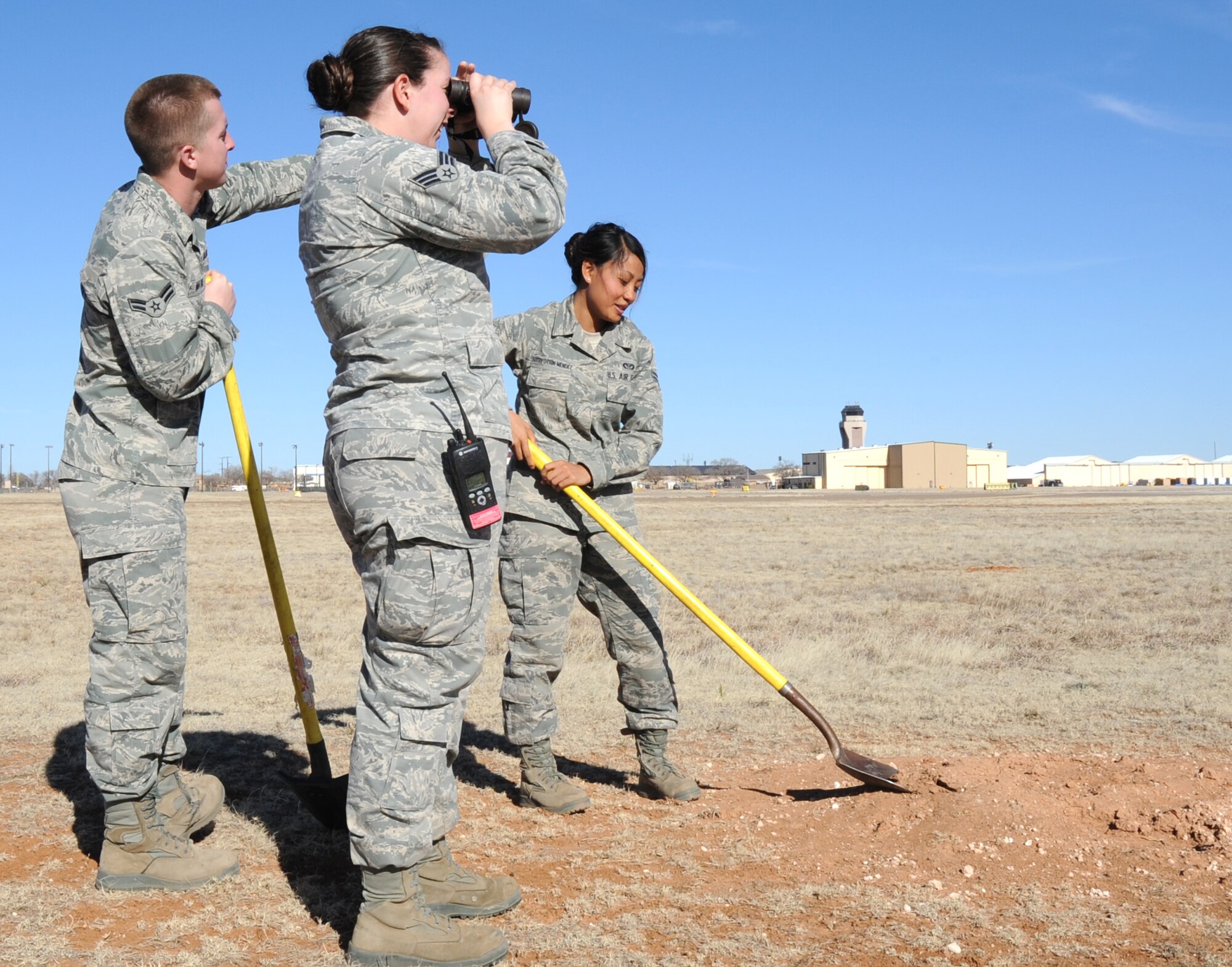 U.S. Air Force Senior Airman C?Belle Tennimon and Airman 1st Class Jacob Mathis survey the area for prairie dogs while Airman 1st Class Lisa Sottiyothin-Mendez levels upturned land near the flightline at Cannon Air Force Base, N.M., Feb. 1, 2012. All three Air Commandos are pest managers who routinely deal with public health concerns at Cannon. (U.S. Air Force photo by Airman 1st Class Alexxis Pons Abascal)  