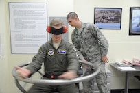 Airman 1st Class Bradley Schlather (right), 359th Aerospace Medicine Squadron Aerospace Physiology technician, assists Maj. Ed Martin, 19th Air Force, as he takes a spin in the barany chair at the Aerospace Physiology unit on Joint Base san Antonio-Randolph Jan. 25. The barany chair is used to detect and to treat chronic airsickness. (U.S. Air Force photo/Rich McFadden) 