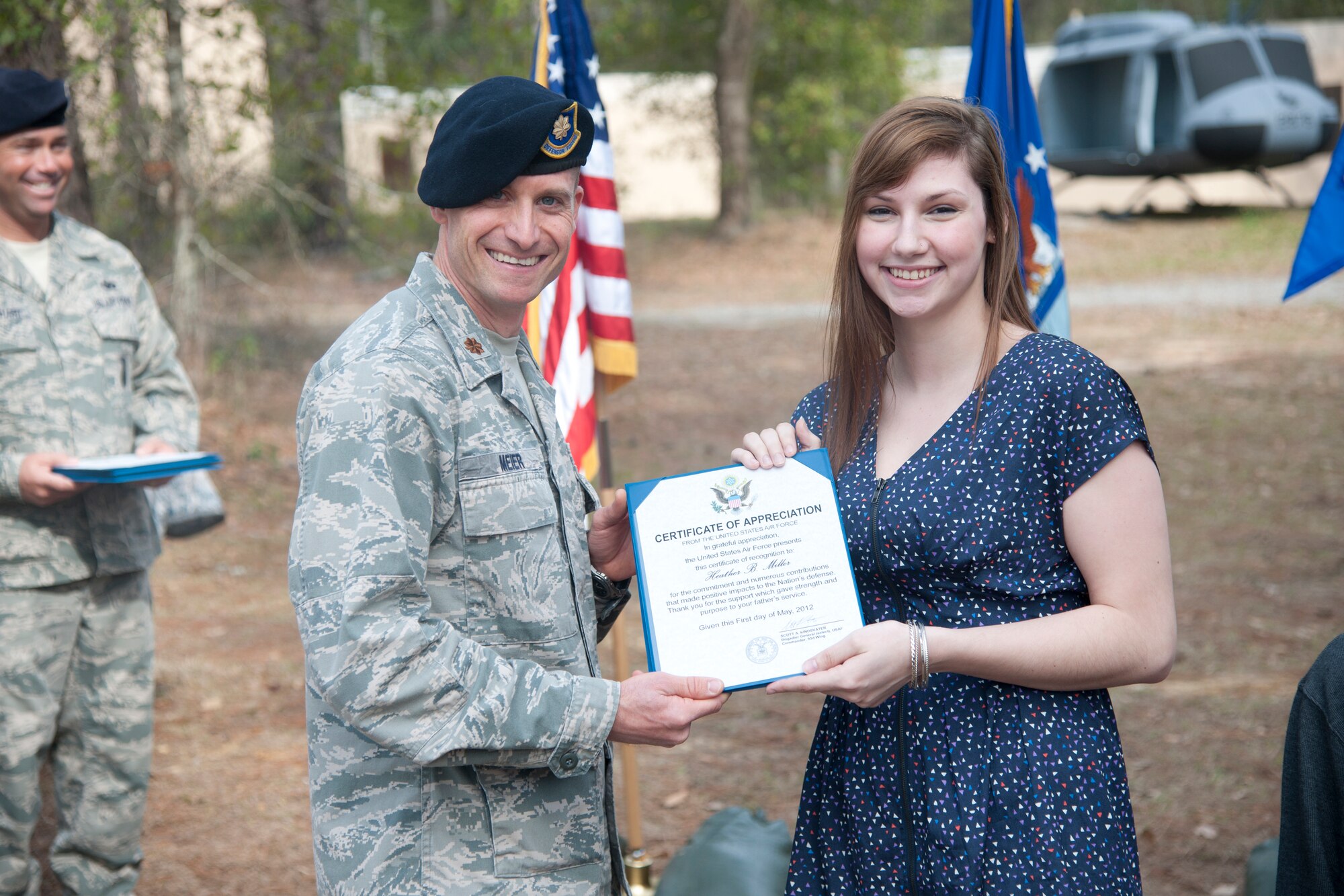 Heather Miller, daughter of retired Chief Master Sgt. Larry Miller, 824th Base Defense Squadron security forces manager, receives an appreciation certificate from U.S. Air Force Maj. James Meier 824th BDS commander at Moody Air Force Base, Ga., Feb. 3, 2012. The certificate thanked Miller for her support during her father’s 28 years in active duty service. (U.S. Air Force Photo by Airmen 1st Class Paul Francis/Released)
