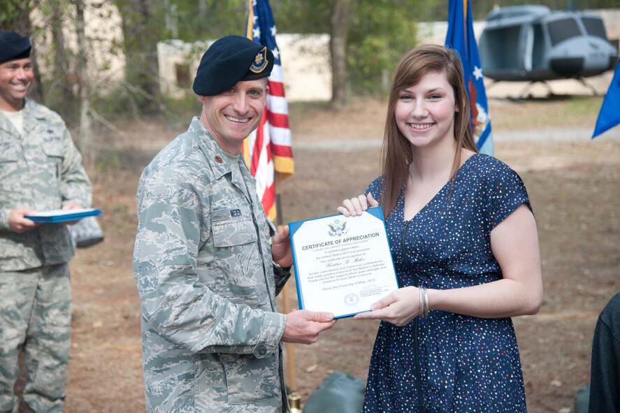 Heather Miller, daughter of retired Chief Master Sgt. Larry Miller, 824th Base Defense Squadron security forces manager, receives an appreciation certificate from U.S. Air Force Maj. James Meier 824th BDS commander at Moody Air Force Base, Ga., Feb. 3, 2012. The certificate thanked Miller for her support during her father’s 28 years in active duty service. (U.S. Air Force Photo by Airmen 1st Class Paul Francis/Released)

