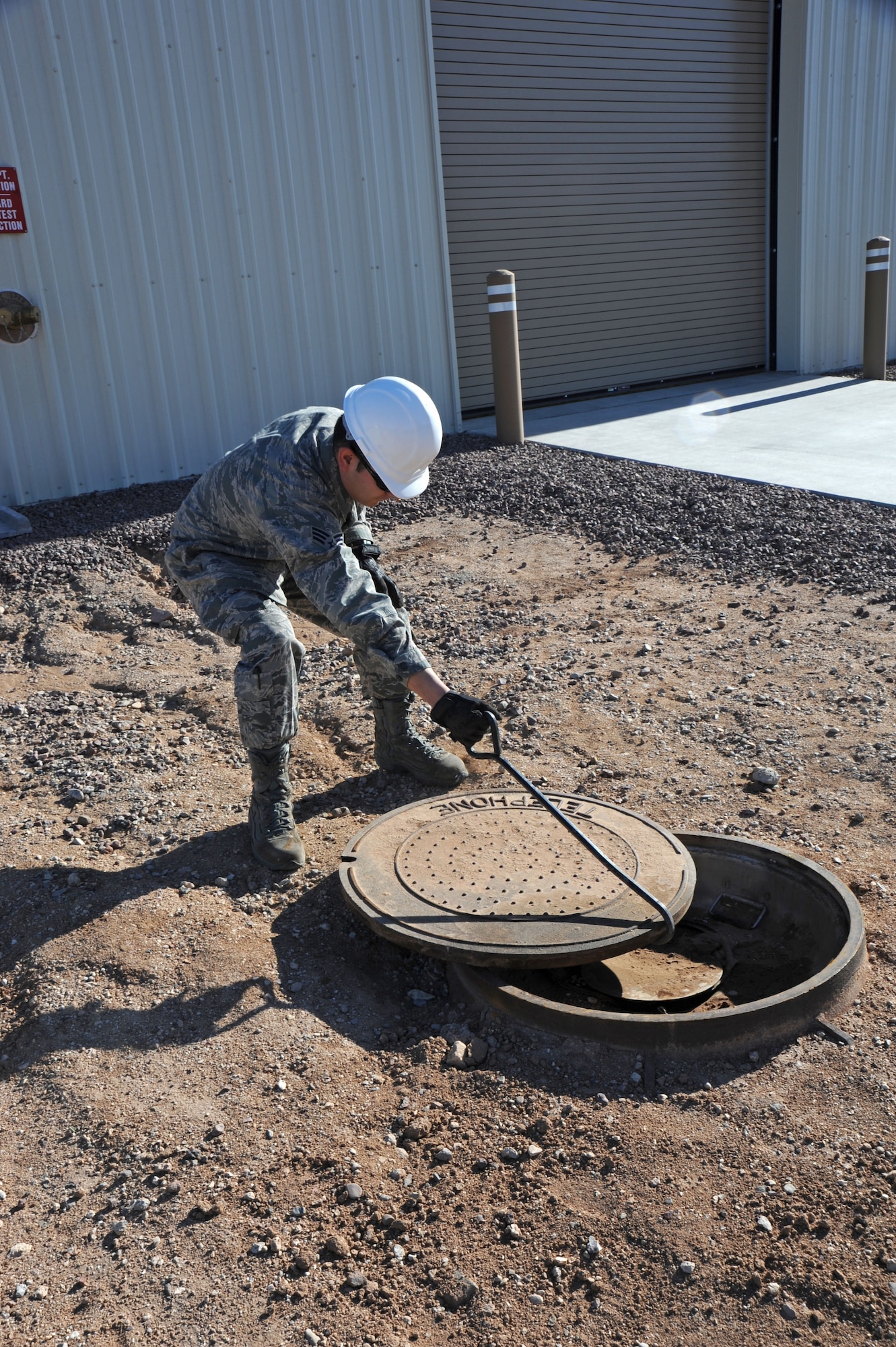 U. S. Air Force Senior Airman Michael Chavez, 355th Communications Squadron voice systems technician, opens a communications manhole at Davis-Monthan Air Force Base, Ariz., Feb. 2, 2012. Airman Chavez performed quality assurance on a contractors’ recent project to ensure everything meets with military standards of work.  (U.S. Air Force photo by Airman 1st Class Camilla Griffin/Released)
