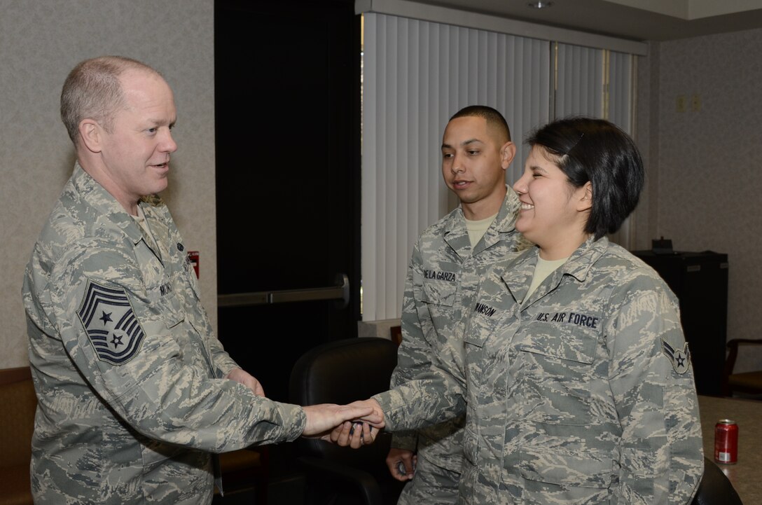 Chief Master Sergeant Chris Muncy, Command Chief Master Sergeant of the Air National Guard, coins Airman 1st Class Shay Swanson, 144th Maintenance Squadron, with Senior Airman Antonio De La Garza, 144th Communications Flight, after an Airmen’s Advisory Council meeting on February 4, 2012. (Air National Guard photo by Tech. Sgt. Robin Meredith)