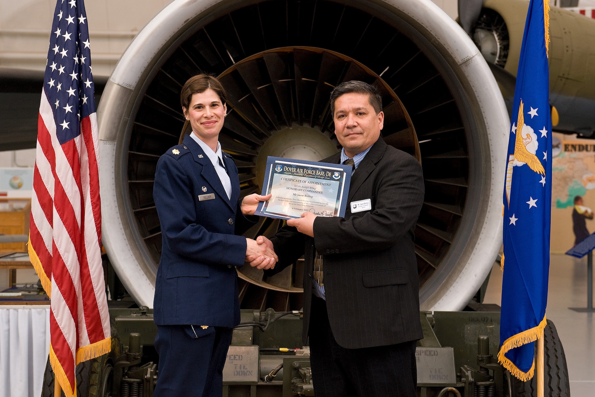 Maj. Asheleigh Gellner, 46th Aerial Port Squadron commander, welcomes incoming Honorary Commander Jason Bishop, the regional sales manager for Pepsi, at the Honorary Commander Induction Ceremony at the Air Mobility Command Museum Feb. 4. Commanders from the 436th and 512th Airlift Wings, Air Force Mortuary Affairs Operations, and Joint Personal Effects Depot recognized outgoing honorary commanders and inducted new local community leaders during the event. (U.S. Air Force photo by Roland Balik)