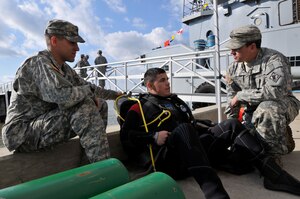 U.S. Army Spc. Javier Novoa (center), a 74th Dive Detachment engineer diver, serves as a standby diver with Spc. Kevin Nagel (left), on hand as Novoa's tender, and Staff Sgt. Humberto Santiago (right), supervising while members of the detachment work on patching a portion of the Large Tug-805 at Fort Eustis' 3rd Port Feb. 2, 2012. (U.S. Army photo by Sgt. 1st Class Kelly Jo Bridgwater/Released)