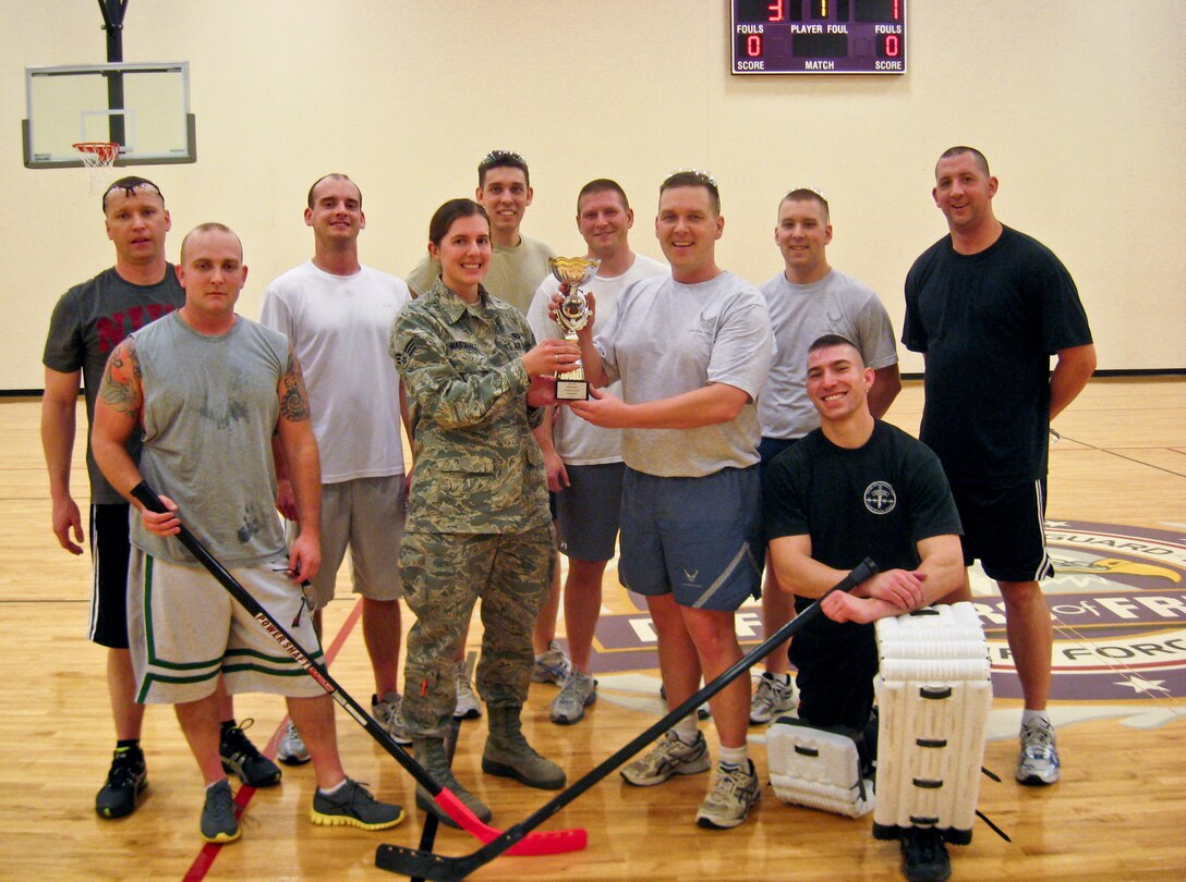 Senior Airman Charlotte Marshall, 934th Force Support Squadron, presents the floor hockey championship trophy to Lt. Col. Ted Ruminsky, 934th Security Forces Squadron commander. The SFS AGR team defeated the Comm Squadron in the title game. (Courtesy photo)