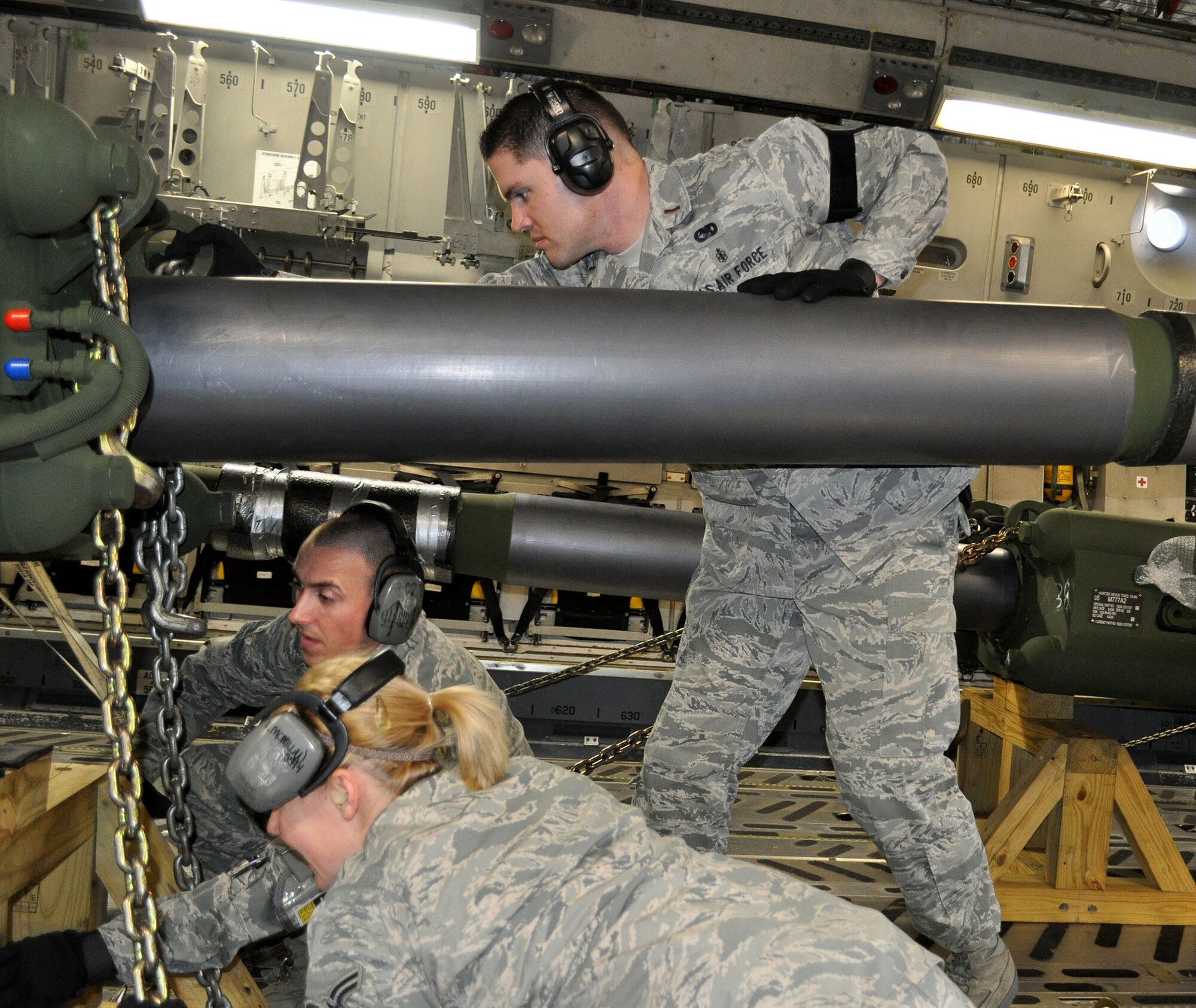 TRAVIS AIR FORCE BASE, Calif. --Airmen 1st Class Lauralee McMillan and Charles Laas use chains to secure a howitzer while 2nd Lt. Justin Johnson holds it steady. Travis aerial porters work together, active and Reserve, as "one team, no seam," to get aircraft loaded and on the way. Feb. 3, the port "dawgs" loaded two howitzers, and eight pallets of cargo, onto a C-5 traveling "down under." McMillan and Laas are with the 60th APS, and the lieutenant is with the 349th's 55th APS. (U.S. Air Force photo/Senior Master Sgt. Ellen Hatfield) 