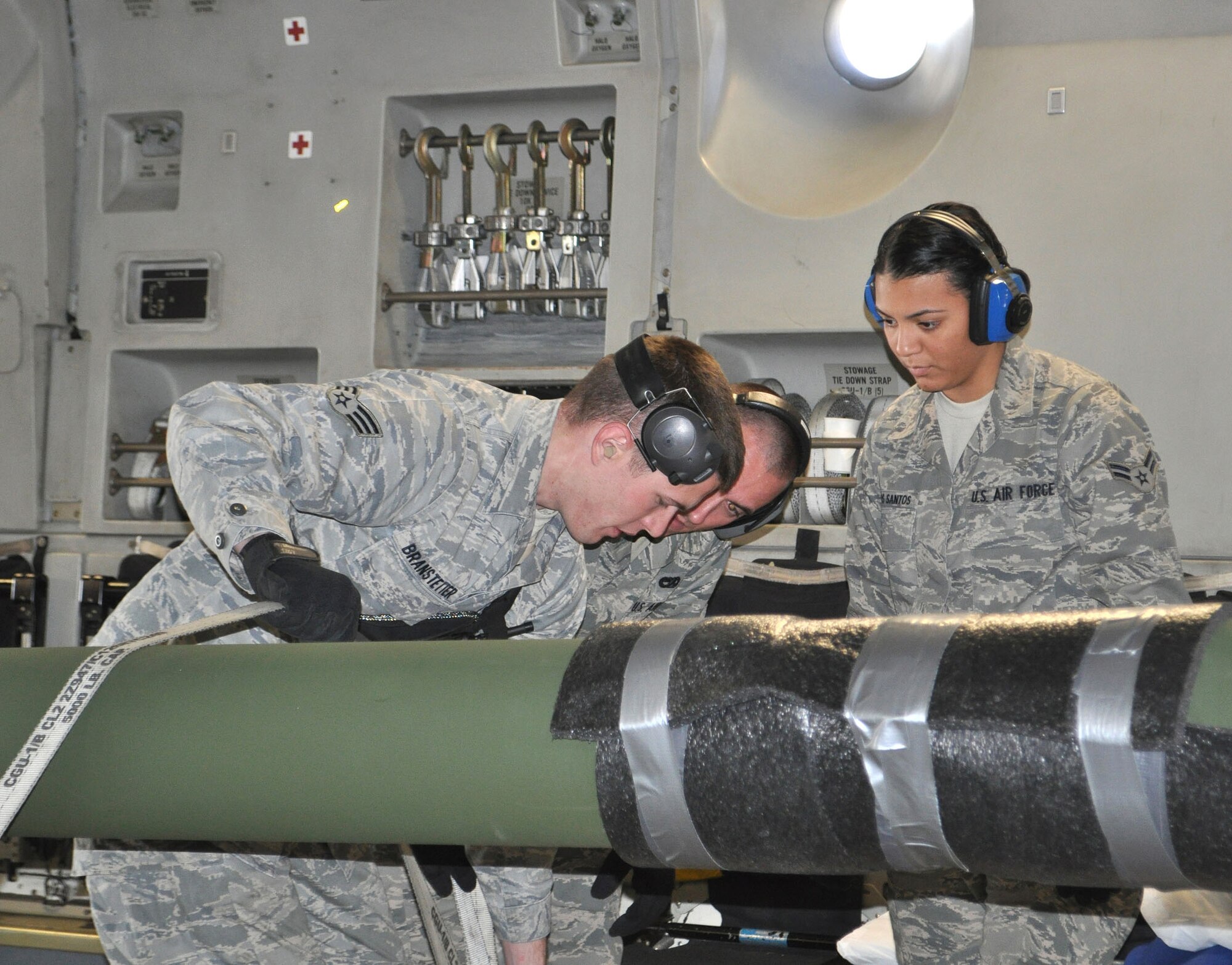 TRAVIS AIR FORCE BASE, Calif. -- From the left: SrA Matt Branstetter, instructs A1Cs Charles Laas, and Vanuce Dias Dos Santos, in the use of straps to stabilize a howitzer for transport aboard a C-5. Two howitzers were lowered and locked down with plenty of chains for the long flight. Branstetter and Laas are assigned to the 60th APS, and Dias Dos Santos is with the Reserve wing's 55th APS. Travis aerial porters are truly "one team, no seam." (U.S. Air Force photo/Senior Master Sgt. Ellen Hatfield)