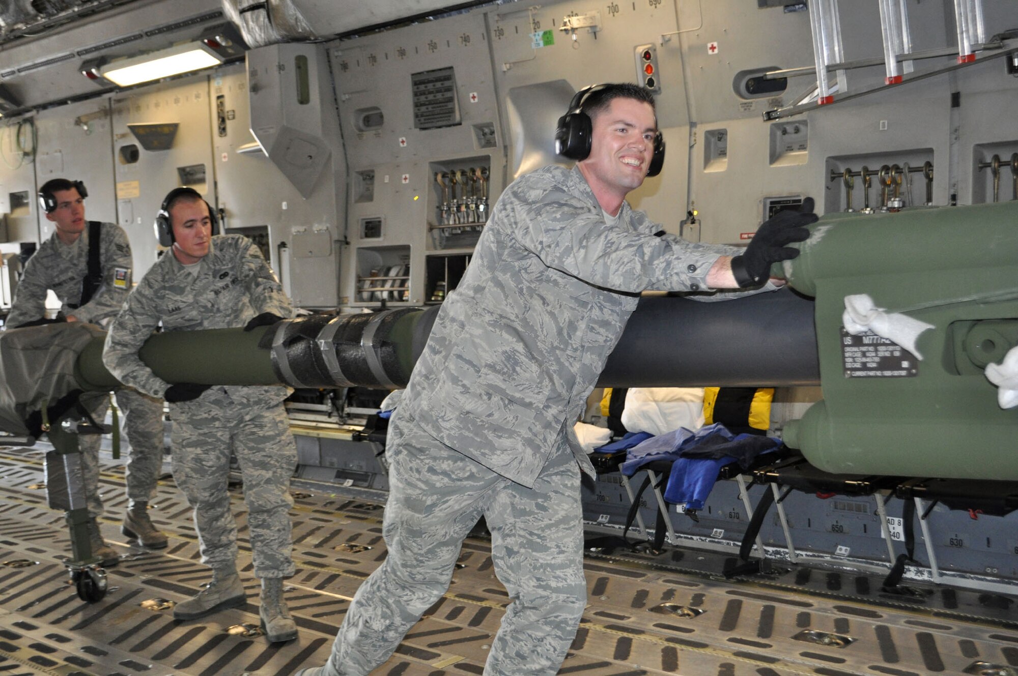 TRAVIS AIR FORCE BASE, Calif. -- Loading two howitzers, plus eight pallets of equipment onto a C-5 on a Friday afternoon, was all in a day's work for these Travis Air Force Base aerial port "dawgs." Easing a howitzer into place here, are, from the left, Senior Amn. Matt Branstetter, team leader, and Airman 1st Class Charles Laas, both with the 60th APS, and 2nd Lt. Justin Johnson, with the Reserve's 55th APS. (U.S. Air Force photo/Senior Master Sgt. Ellen Hatfield)