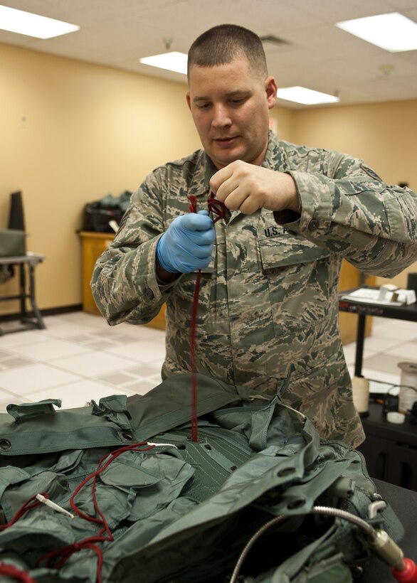 Staff Sgt. Andrew Wahlin, 28th Operations Support Squadron aircrew flight equipment craftsman, threads the side flap closure cord during a parachute inspection at Ellsworth Air Force Base, S.D., Jan. 24, 2012. Every parachute must be disassembled, inspected, and repacked at least once every five years to ensure all parachutes are in serviceable condition.  (U.S. Air Force photo by Airman Alystria Maurer/Released) 