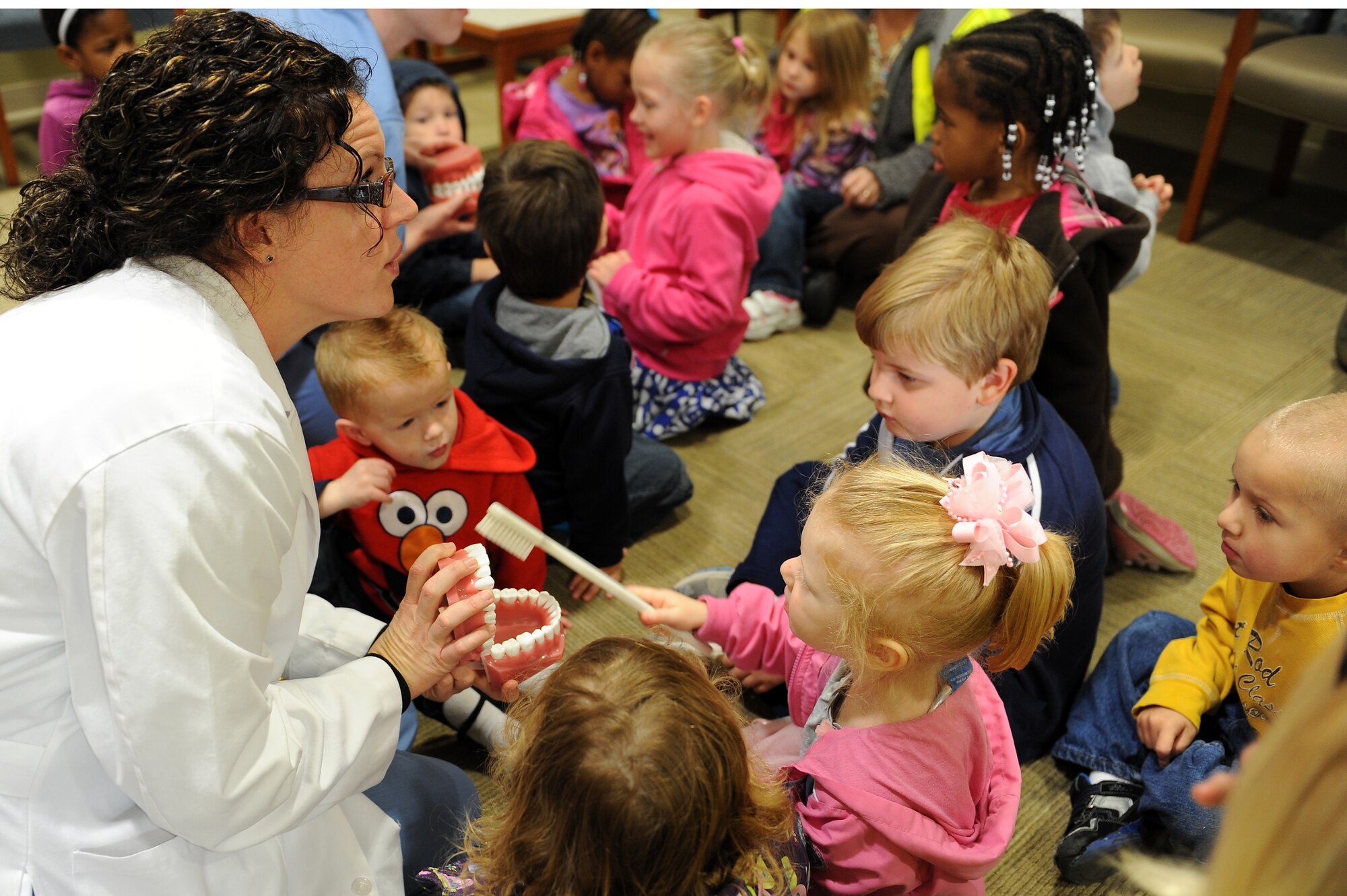 Layton Fillion, 23d Aerospace Medicine Squadron hygienist, teaches children from the Child Development Center the important areas to brush at Moody Air Force Base, Ga., Feb. 8, 2012. Children should have their first teeth cleaning beginning at age 1. (U.S. Air Force photo by Staff Sgt. Ciara Wymbs/Released) 