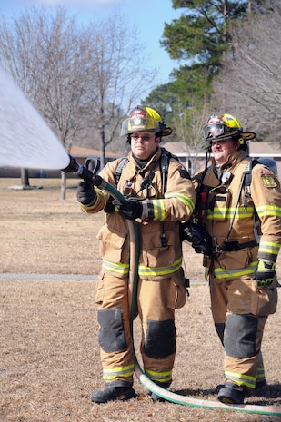 Firefighter Dominic Rend mans the nozzle as Firefighter Michael Brady holds down the hose with his foot and supports his partner as they simulate extinguishing a fire during an exercise at Joint Base Charleston – Weapons Station Feb. 2. The exercise was held to test the unit’s response to a simulated fire at a home in the Menriv Housing area. Rend and Brady are both assigned to the 628th Civil Engineer Squadron, Civil Engineer Fire Department. (U.S. Navy photo/Petty Officer 1st Class Jennifer Hudson)